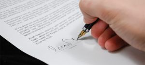A person signing a document after learning the things to know about moving contracts.