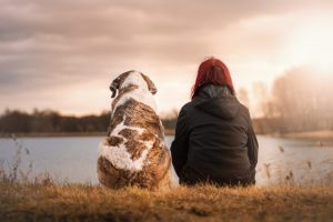 A girl and her dog sitting by a lake
