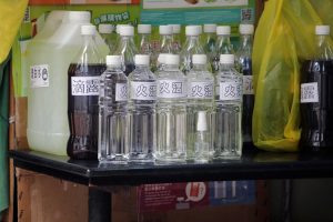 bottles of several sizes with several different liquids on a table
