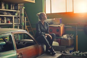 A woman sitting on a car in a garage