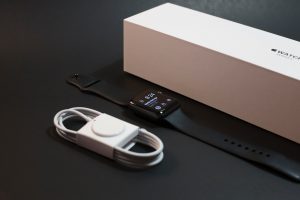 cords and a smart watch next to a white box
