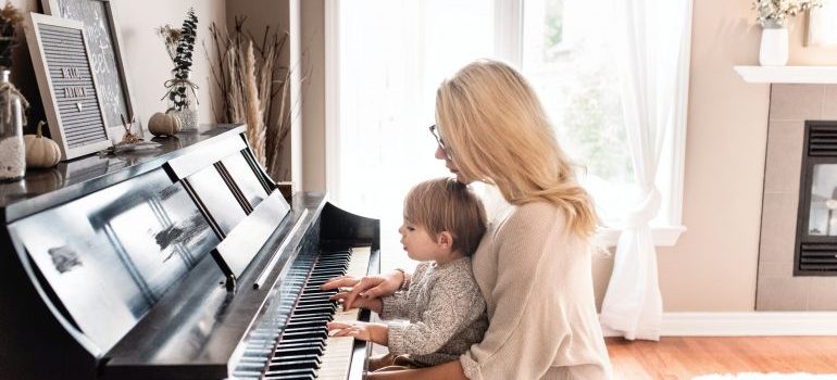 A woman playing a piano holding a child in her lap