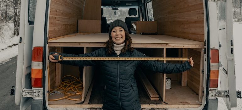 a woman standing in front of the moving truck with a measuring tape