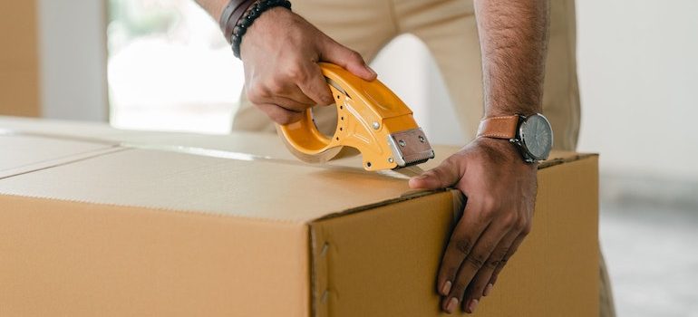 man sealing a box with duct tape