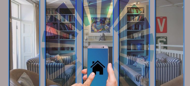 a man holds a mobile phone with a house icon and looks through a glass wall inside the house