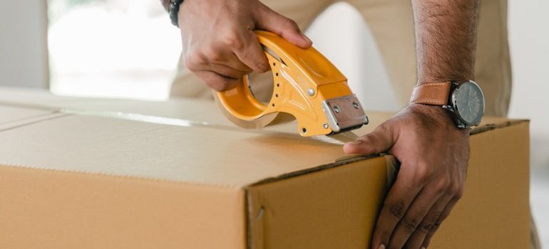 person sealing a cardboard box