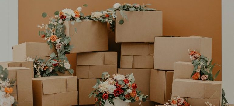 A lot of cardboard boxes stacked on top of one another, some covered with flowers representing the process of moving