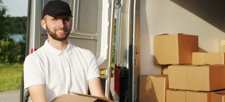 A smiled man holding moving boxes
