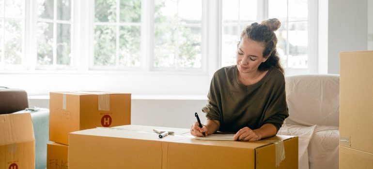 A woman writing a plan on a moving box