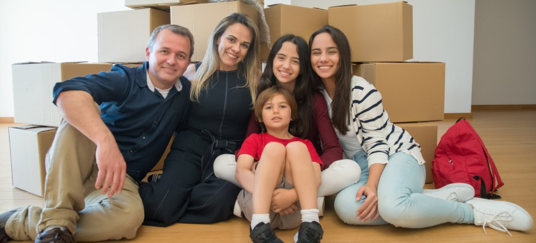 a happy family of five sitting in front of the packed cardboard boxes