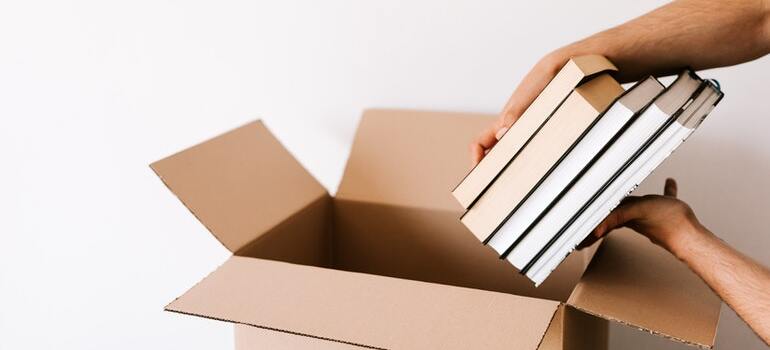 A person packing books in a movign box