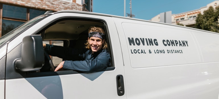 A man smiling and driving a moving van