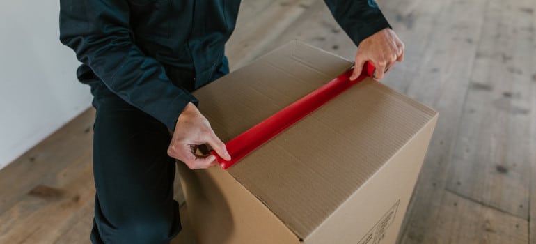 Packing services Miami sealing a box with masking tape