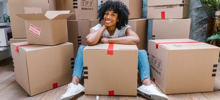 a woman sitting on the floor surrounded by the moving boxes
