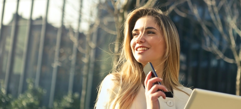 woman smiling while holding her phone