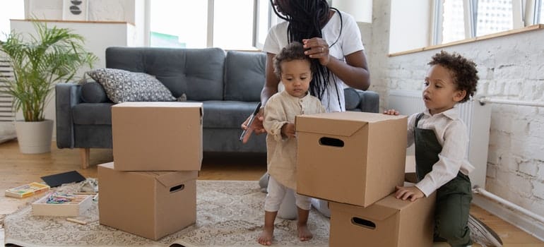 a woman with two small kids playing with moving boxes