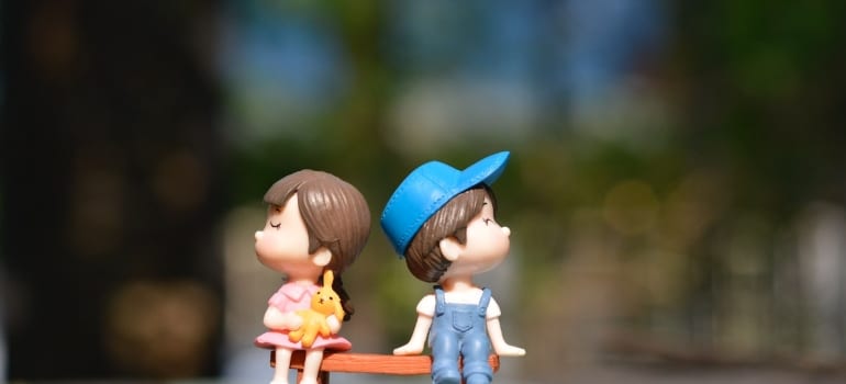 boy and girl toys sitting on a bench