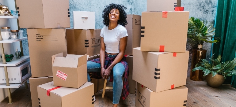 woman sitting surrounded by moving boxes thinking how to find moving and storage solutions in Florida