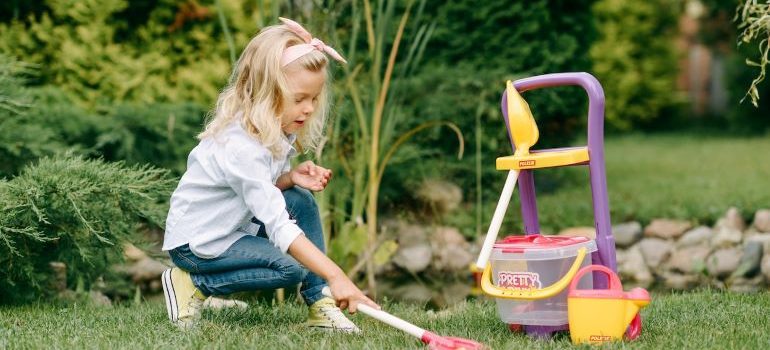 a child playing outside in the garden with her plastic toys